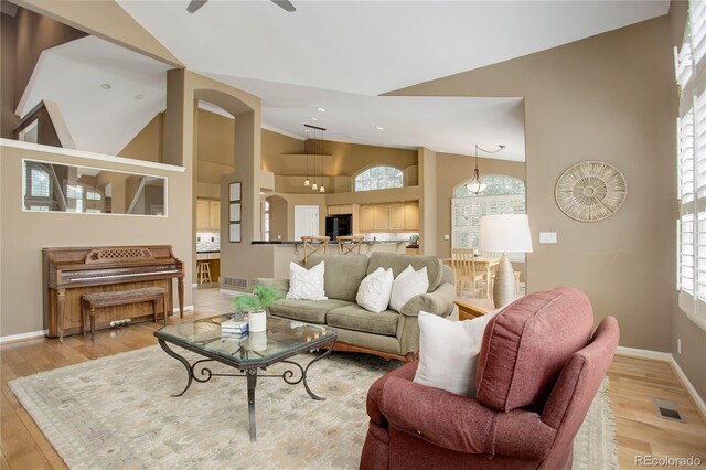 living room featuring high vaulted ceiling, ceiling fan, and light hardwood / wood-style flooring