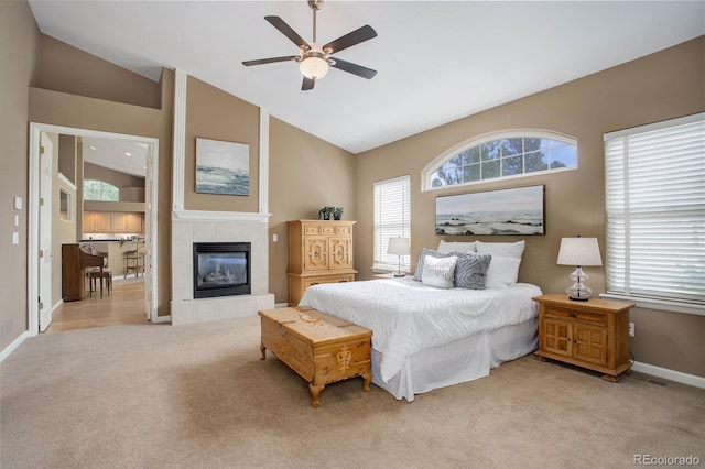 bedroom featuring a fireplace, ceiling fan, light carpet, and lofted ceiling