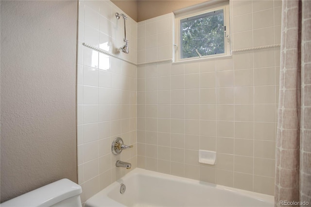 bathroom with tiled shower / bath and toilet