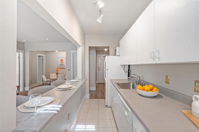 kitchen with white cabinets, white dishwasher, sink, and light tile patterned flooring