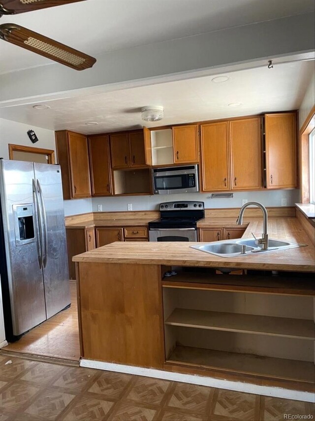 kitchen featuring stainless steel appliances, a ceiling fan, a sink, and open shelves