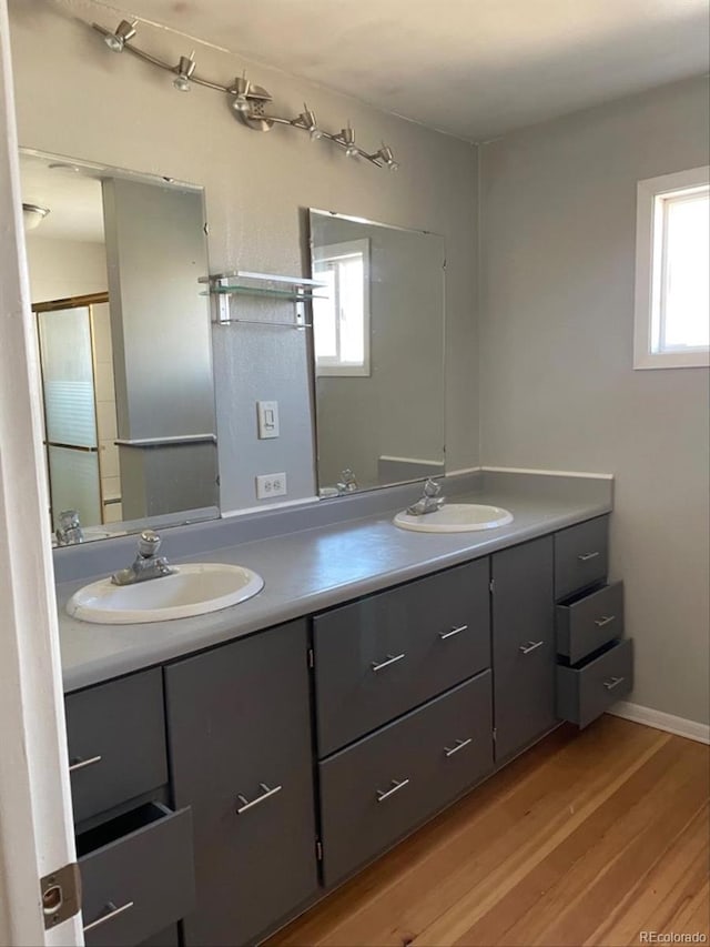 full bathroom with double vanity, a sink, and wood finished floors