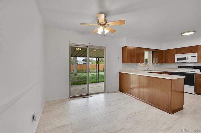 1304 De Reamer Cir, Colorado Springs, CO 80915 - kitchen with white microwave, electric range, a ceiling fan, a sink, and a peninsula