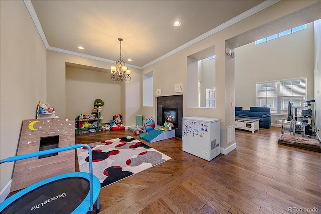 recreation room with ornamental molding, a chandelier, a glass covered fireplace, baseboards, and recessed lighting