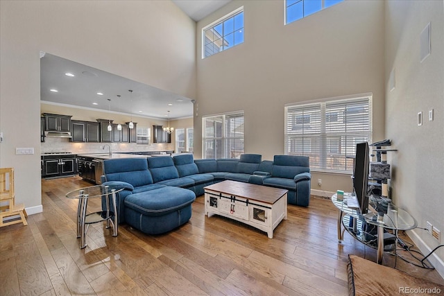 living room with hardwood / wood-style floors, a high ceiling, baseboards, and recessed lighting