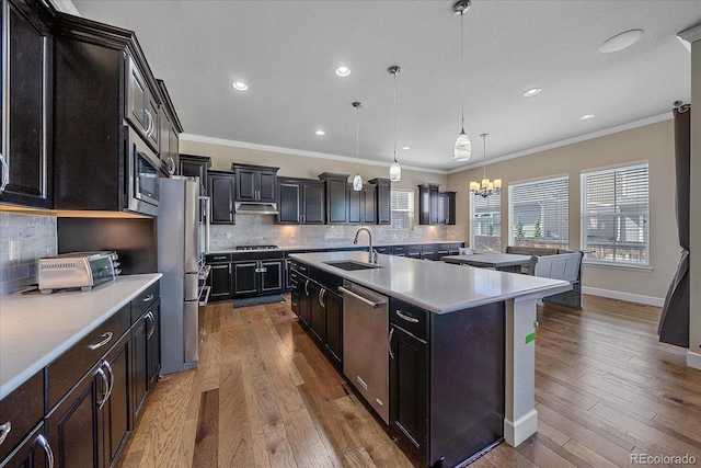 kitchen featuring a sink, stainless steel appliances, crown molding, tasteful backsplash, and light countertops