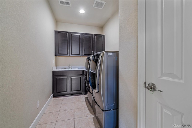 clothes washing area with washer and clothes dryer, cabinet space, baseboards, light tile patterned flooring, and a textured wall