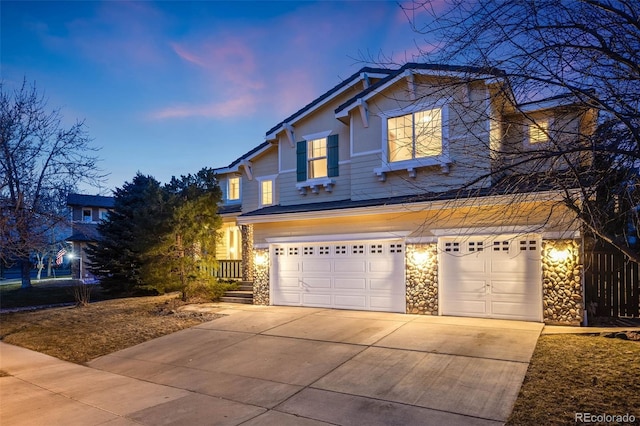 traditional-style home featuring concrete driveway, an attached garage, and stone siding