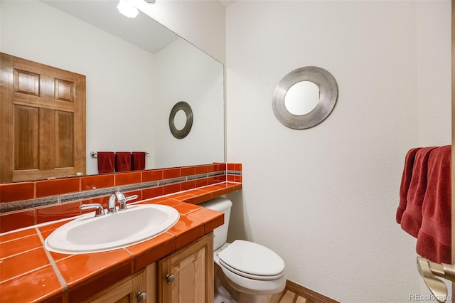 half bath with backsplash, toilet, and vanity