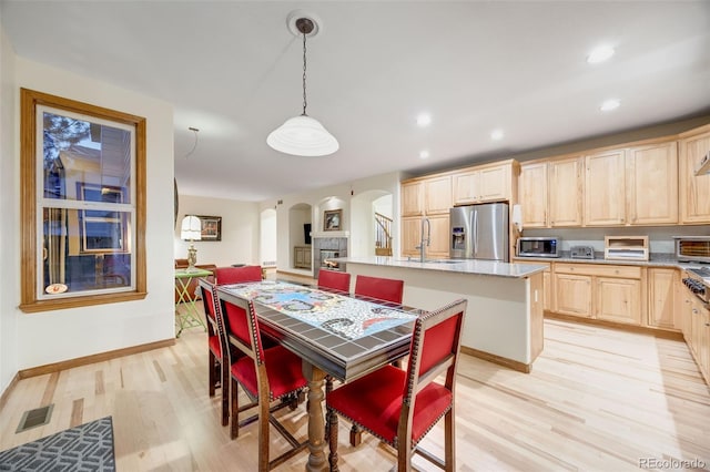 dining room featuring visible vents, baseboards, recessed lighting, arched walkways, and light wood-style floors