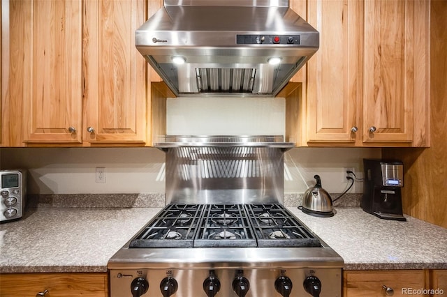 kitchen featuring range with gas stovetop, light countertops, and wall chimney range hood