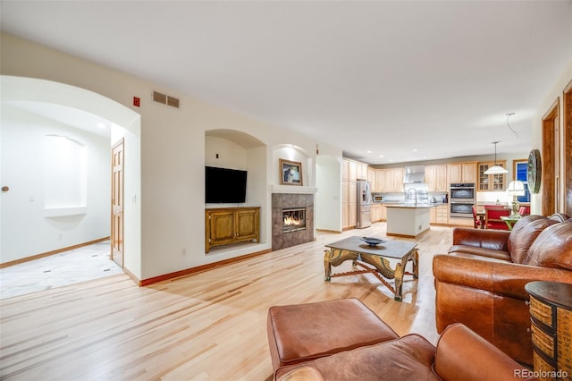 living room with visible vents, baseboards, a fireplace, recessed lighting, and light wood-style floors