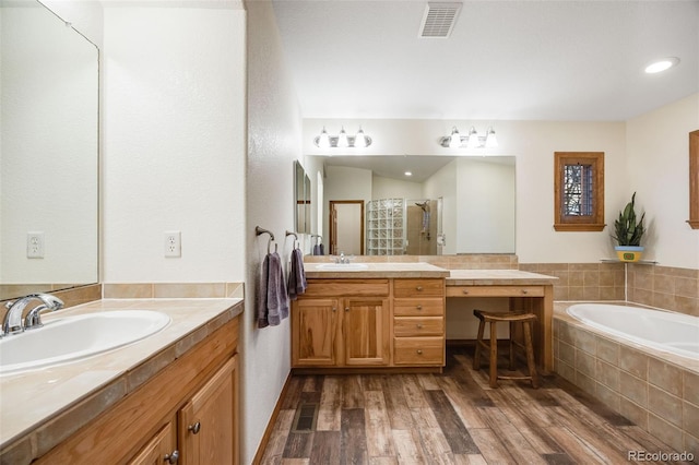 full bath with visible vents, a shower stall, wood finished floors, and a sink