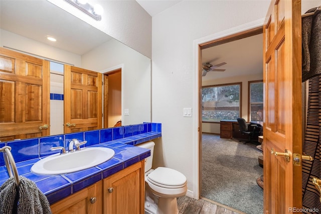 bathroom with toilet, vanity, ceiling fan, and wood finished floors