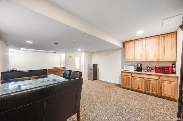 kitchen with white microwave, visible vents, light brown cabinets, light countertops, and light carpet