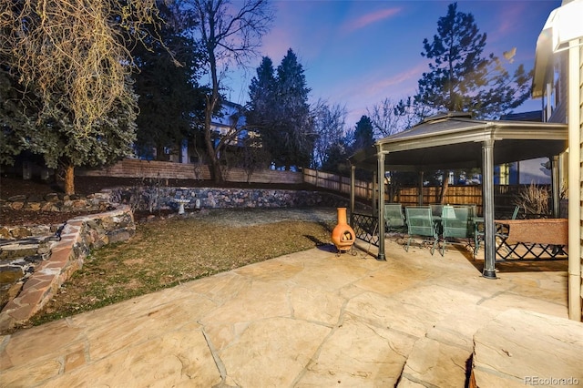 patio terrace at dusk featuring a gazebo and a fenced backyard