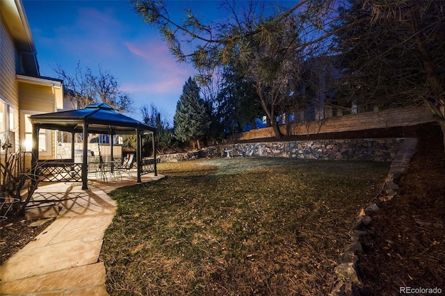 yard at dusk with a gazebo, a patio, and fence