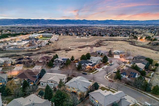 aerial view at dusk featuring a mountain view and a residential view