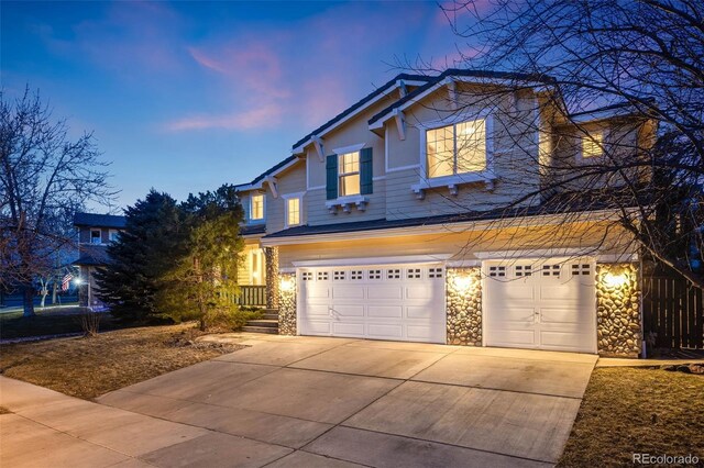 craftsman-style house featuring driveway, stone siding, and a garage