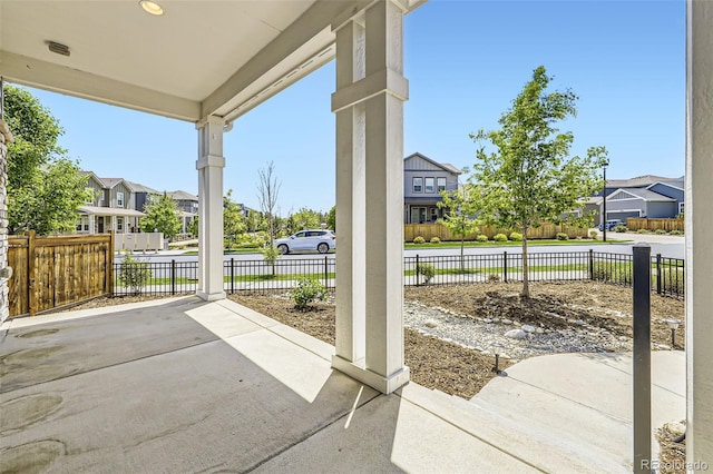 view of patio / terrace featuring a residential view, a water view, and fence