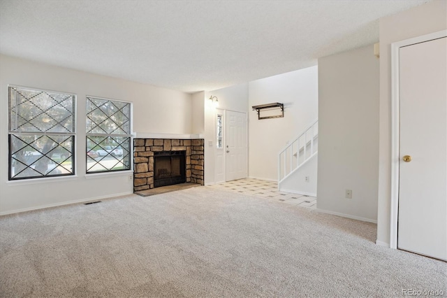 unfurnished living room with carpet, baseboards, a stone fireplace, and stairs