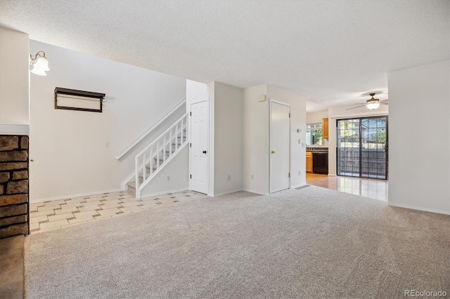 unfurnished living room featuring a ceiling fan, stairway, light colored carpet, a textured ceiling, and baseboards