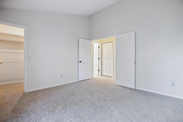 unfurnished bedroom featuring carpet, a spacious closet, and baseboards
