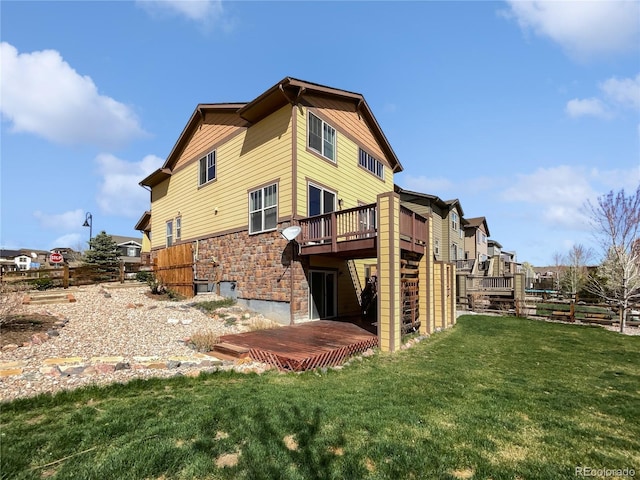 back of house with a lawn, stone siding, and a wooden deck