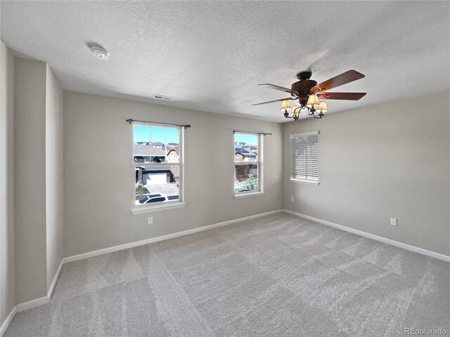 carpeted spare room with visible vents, ceiling fan, and baseboards