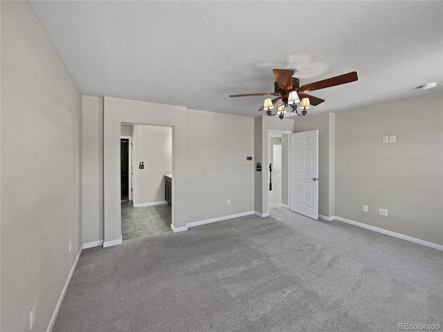 carpeted spare room with ceiling fan, baseboards, and a textured ceiling