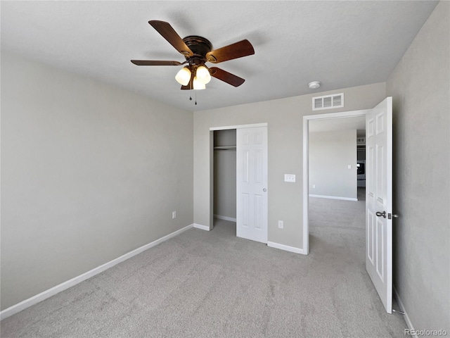 unfurnished bedroom featuring ceiling fan, a closet, visible vents, carpet floors, and baseboards