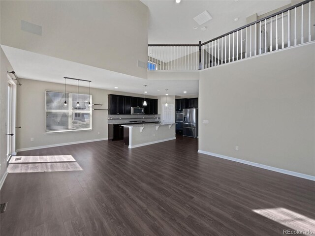 unfurnished living room featuring a high ceiling, baseboards, and dark wood-style floors