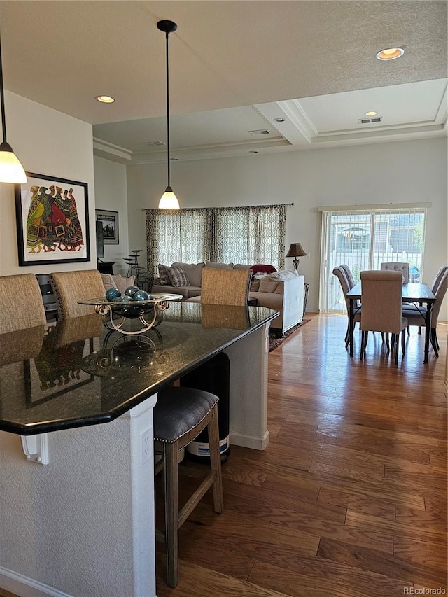 kitchen with a kitchen breakfast bar, hanging light fixtures, and dark hardwood / wood-style floors