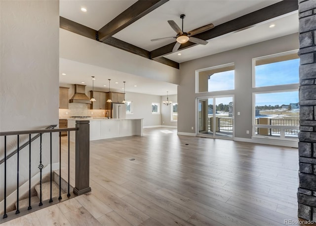 living room with beam ceiling, ceiling fan with notable chandelier, and light hardwood / wood-style flooring