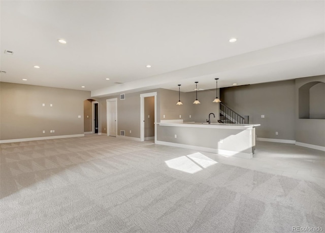 unfurnished living room featuring light carpet and sink