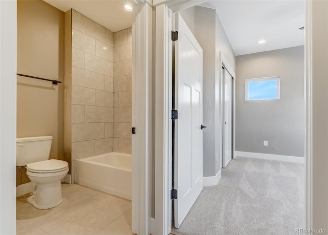 bathroom with tile patterned flooring, tiled shower / bath combo, and toilet