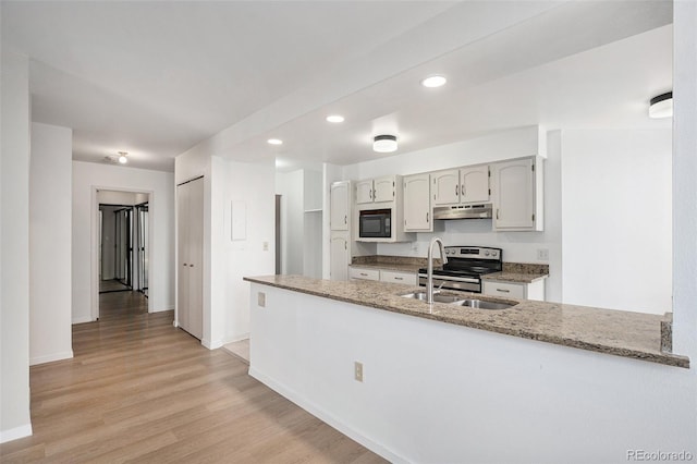 kitchen with black microwave, stainless steel range with electric cooktop, a sink, a peninsula, and under cabinet range hood