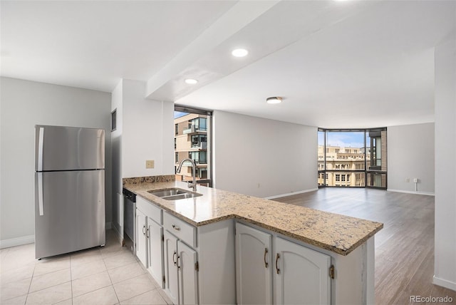 kitchen featuring baseboards, a sink, a peninsula, and stainless steel appliances