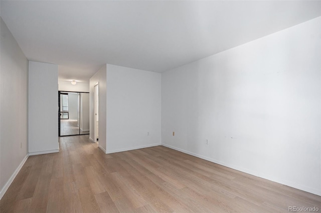 spare room featuring light wood-style floors and baseboards