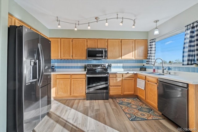 kitchen featuring a sink, light wood finished floors, light countertops, stainless steel appliances, and tasteful backsplash