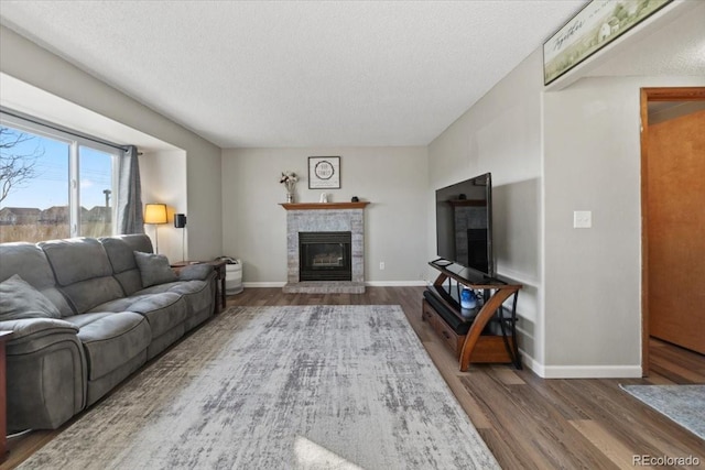 living area featuring a textured ceiling, baseboards, a fireplace, and wood finished floors