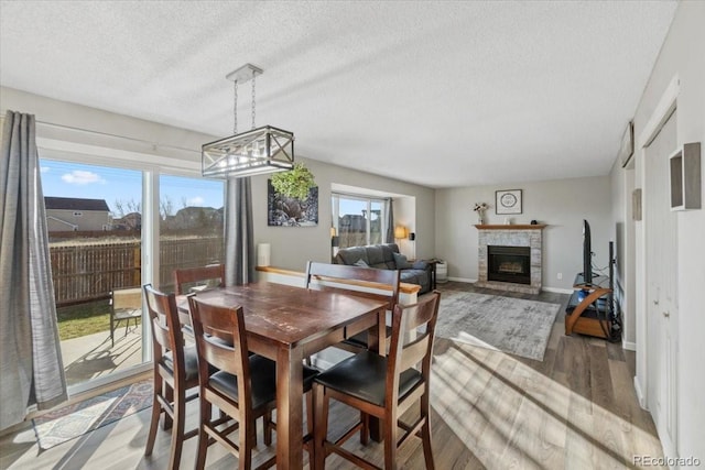 180 S Carlton St, Castle Rock, CO 80104 - dining room with wood finished floors, a glass covered fireplace, a textured ceiling, baseboards, and a chandelier