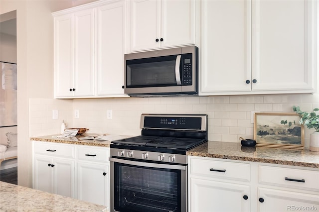 kitchen featuring light stone counters, decorative backsplash, white cabinets, and appliances with stainless steel finishes