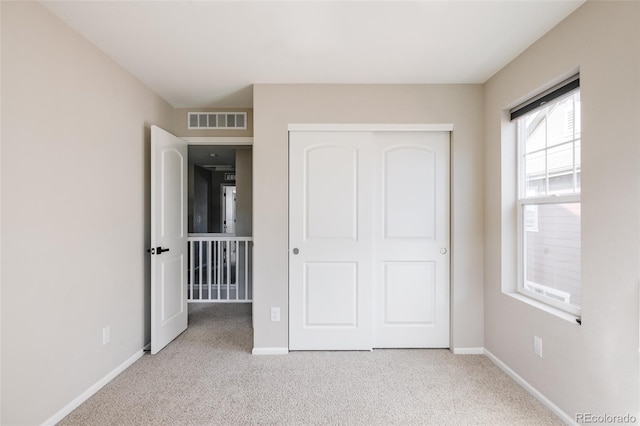 unfurnished bedroom with light carpet and a closet