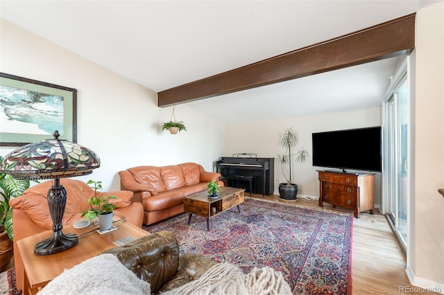 living area featuring light wood-style floors, vaulted ceiling with beams, and baseboards