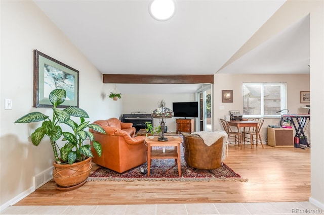 living room featuring lofted ceiling, visible vents, baseboards, and wood finished floors