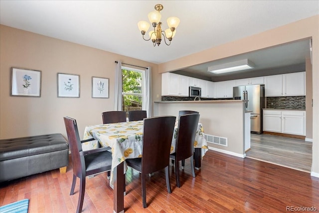 dining space with a chandelier, wood finished floors, and baseboards