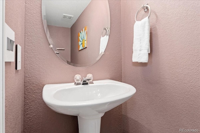 bathroom with a textured wall and a sink