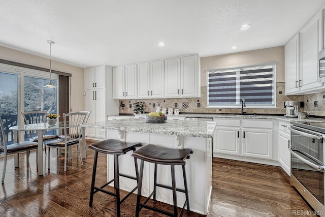 kitchen featuring pendant lighting, white cabinets, a kitchen island, stainless steel appliances, and sink