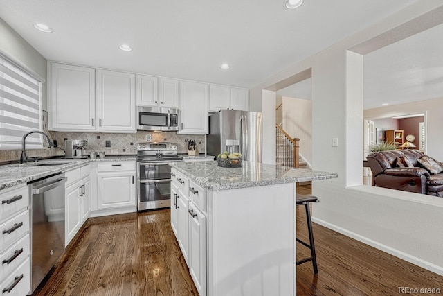 kitchen featuring white cabinetry, a kitchen breakfast bar, sink, a kitchen island, and stainless steel appliances